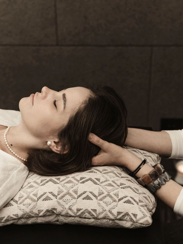 Craniosacral therapy session, gentle hands supporting the head and neck